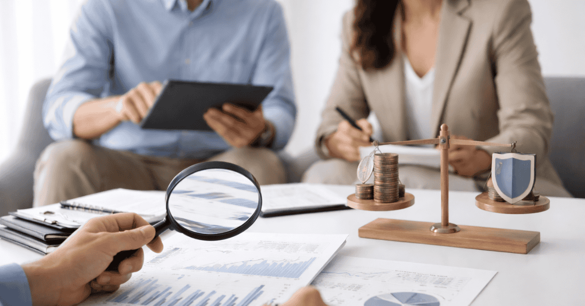 Financial advisors analyzing charts and reports at a table, reviewing investments with risk and return balance using documents and digital devices